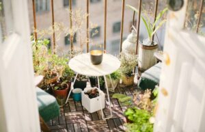 Liten grönskande balkong med cafébord, krukväxter och sittplatser